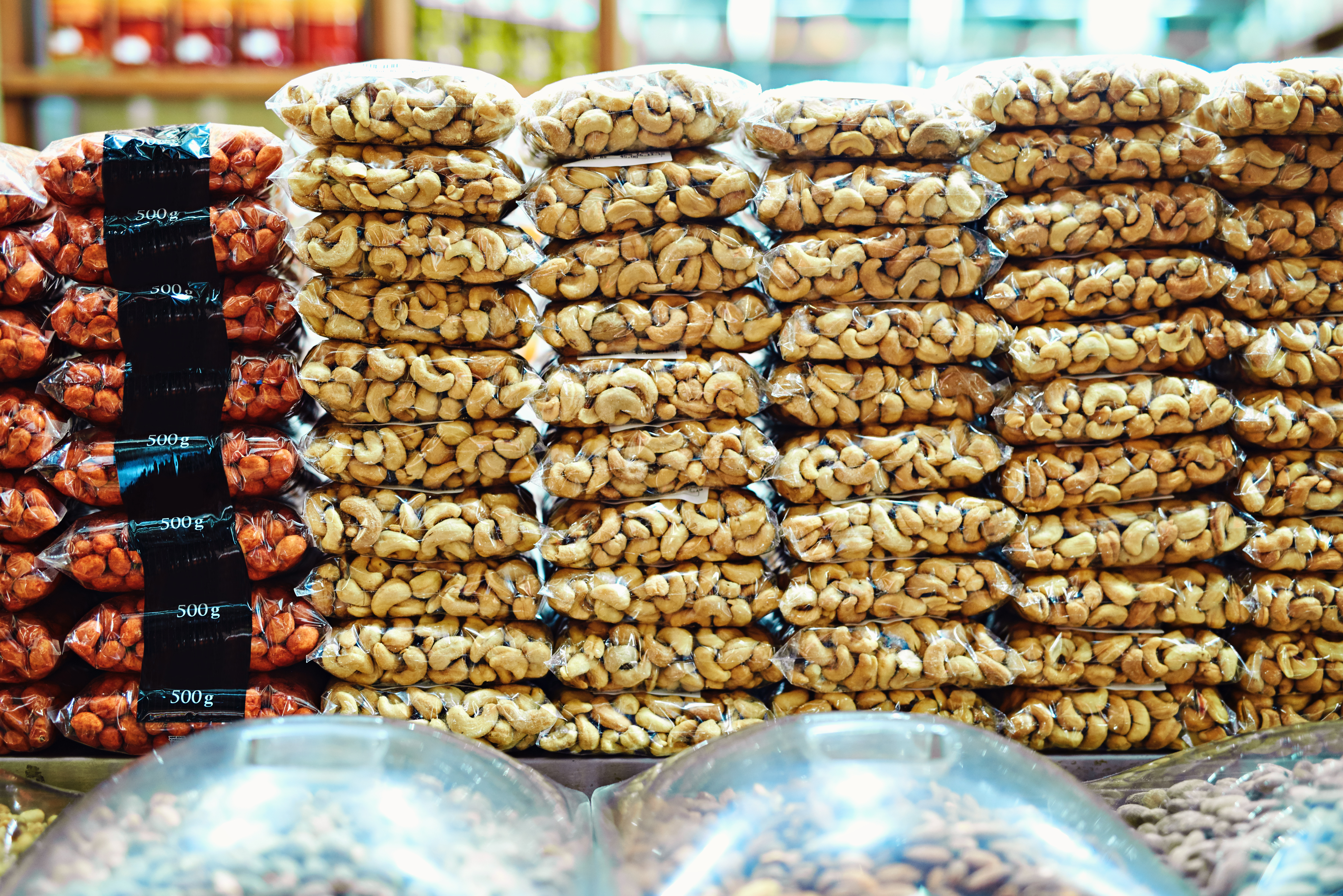 All packed and ready to be bought. packets full of nuts stacked on top of each other ready to be sold at a market during the day